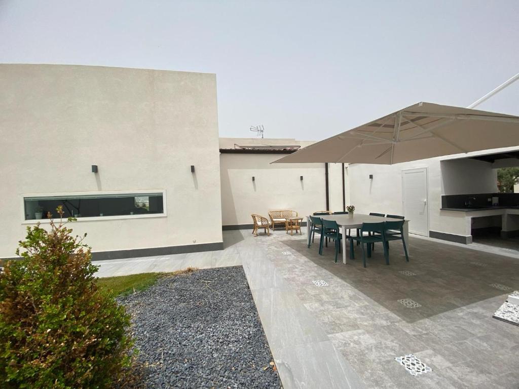 un patio avec une table et un parasol dans l'établissement Villa dei Pioppi Deluxe, à Carini