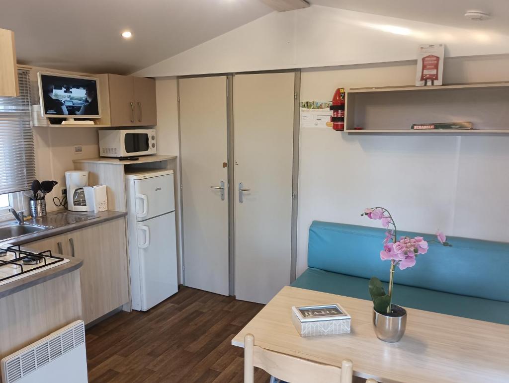 Il comprend une petite cuisine et une salle à manger avec une table. dans l'établissement Mobile-home camping 7 fonts AGDE, à Agde