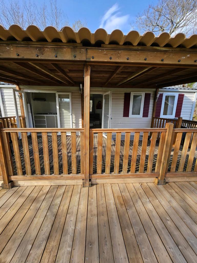 une terrasse en bois avec un auvent sur une maison dans l'établissement Camping familial les Chalets d'Uza, à Uza
