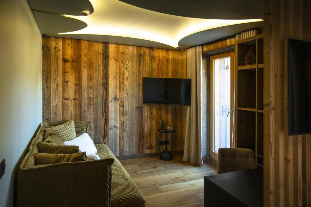 un salon avec un canapé et une télévision dans l'établissement Hotel Beauregard, à La Clusaz