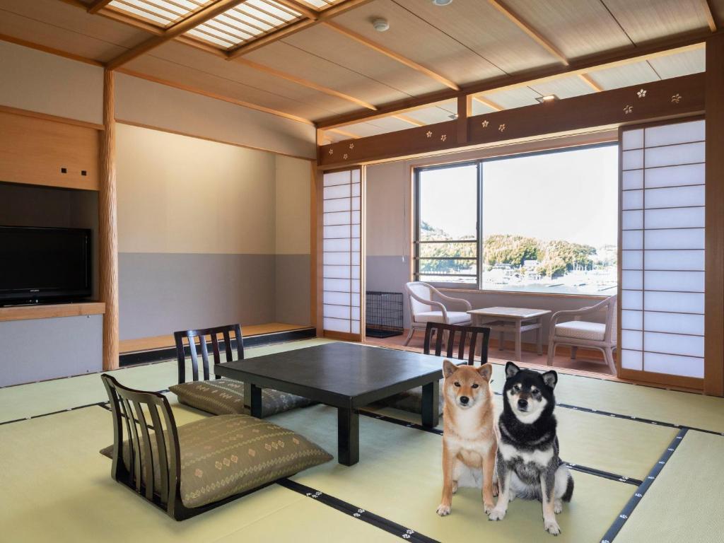 deux chiens assis dans une pièce avec une table dans l'établissement Izumigo Lake Hamana Dog Paradise Hotel, à Hamamatsu