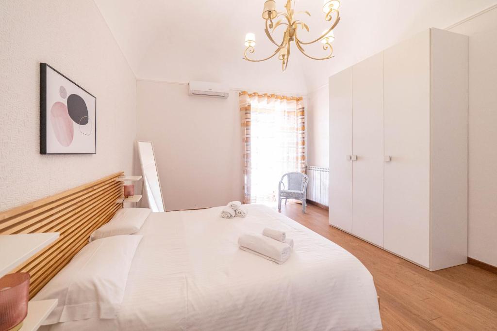 - une chambre blanche avec un grand lit et un lustre dans l'établissement Villa Venere Sicily, à Piedimonte Etneo