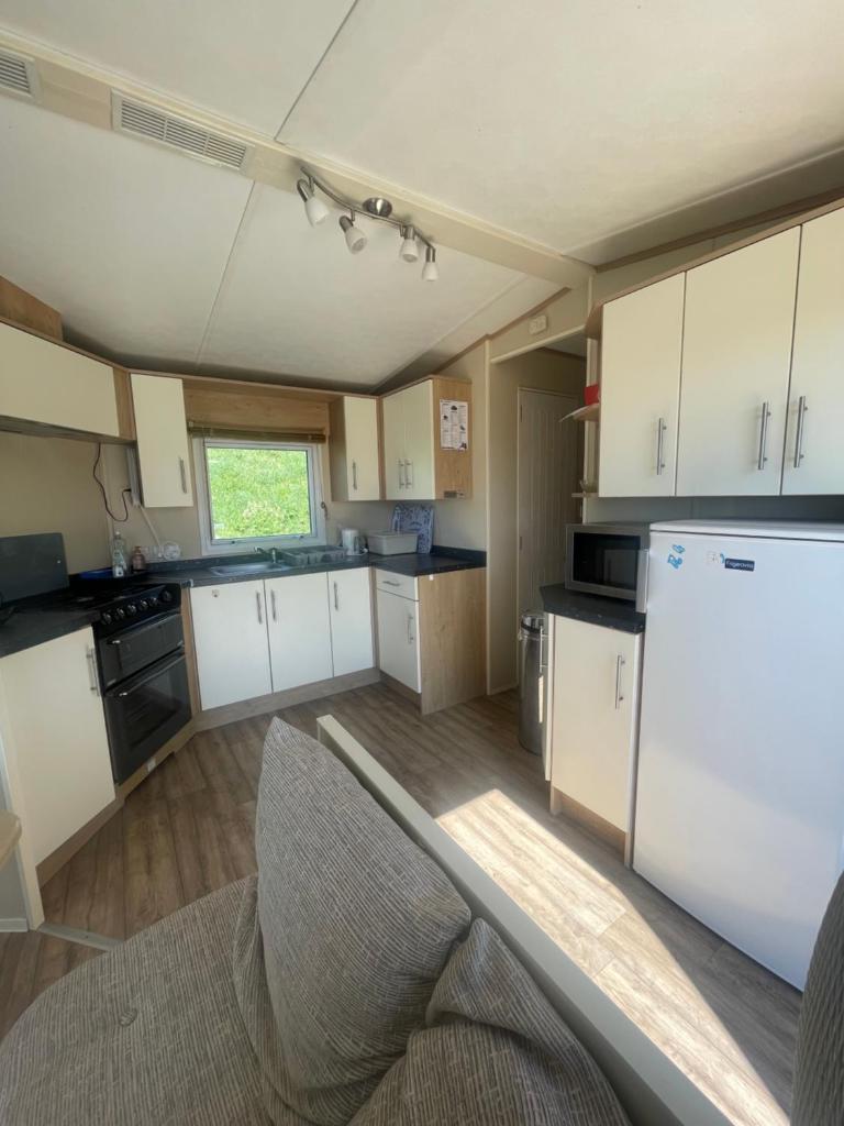 une cuisine avec des armoires blanches et un réfrigérateur blanc dans l'établissement Mobil home au bord de la mer, vue sur la mer camping de la falaise à Equihen-Plage, à Équihen-Plage