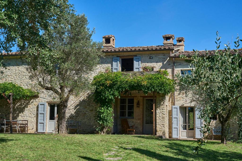 une grande maison en pierre avec une cour herbeuse dans l'établissement Villa Bacciana, à Montone