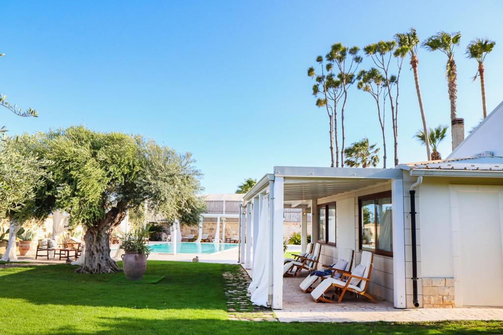 une maison blanche avec des chaises et une cour dans l'établissement Villa Erika piscina privata, à Ispica