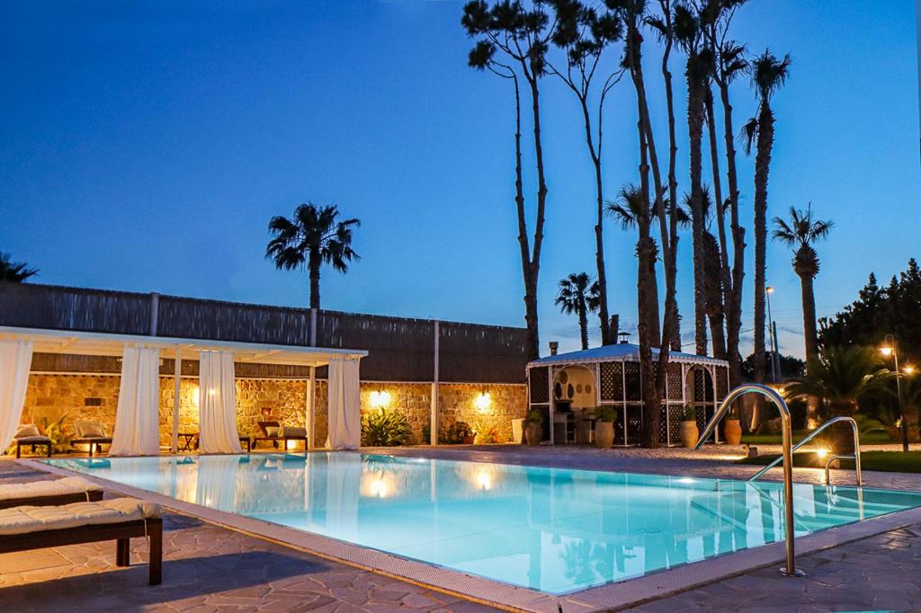 - une grande piscine avec des palmiers la nuit dans l'établissement Villa Erika piscina privata, à Ispica