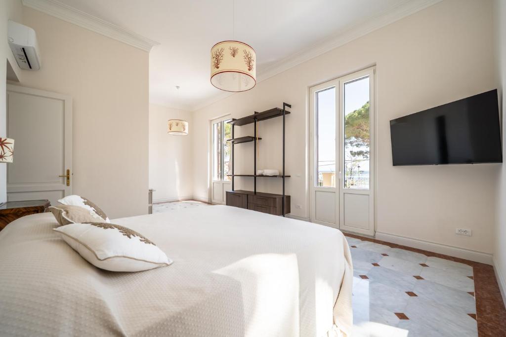 une chambre blanche avec un grand lit et une télévision à écran plat dans l'établissement Villa Hercules Pool & Beach, à Palerme
