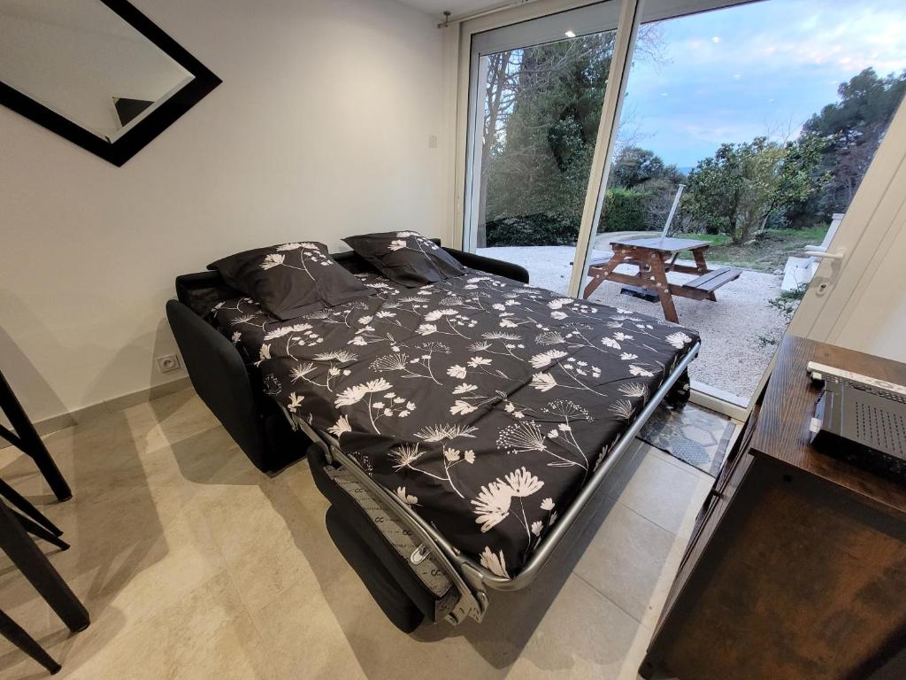 un lit dans une chambre avec une grande fenêtre dans l'établissement Gîte Chrysalide du Luberon, à Cheval-Blanc