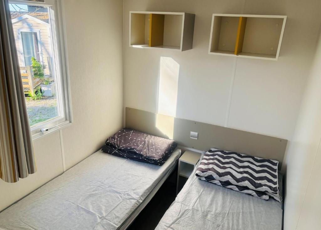 une petite chambre avec deux lits et une fenêtre dans l'établissement camping le clos fleuri, à Vic-la-Gardiole