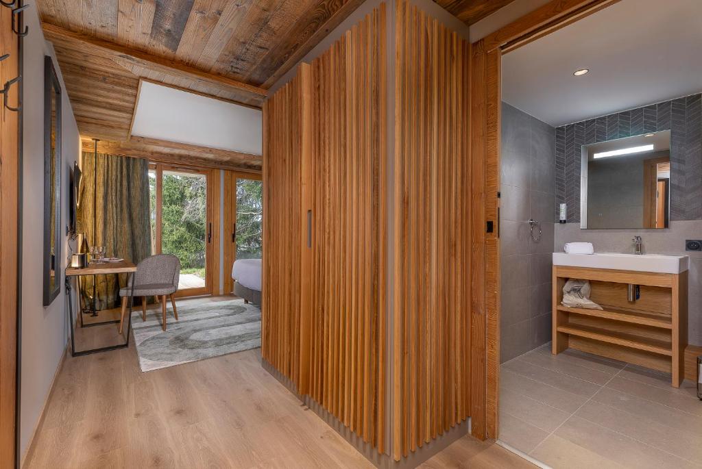 La salle de bains est pourvue de murs en bois et d'un lavabo. dans l'établissement La Cour aux Ecureuils, à Peisey-Nancroix