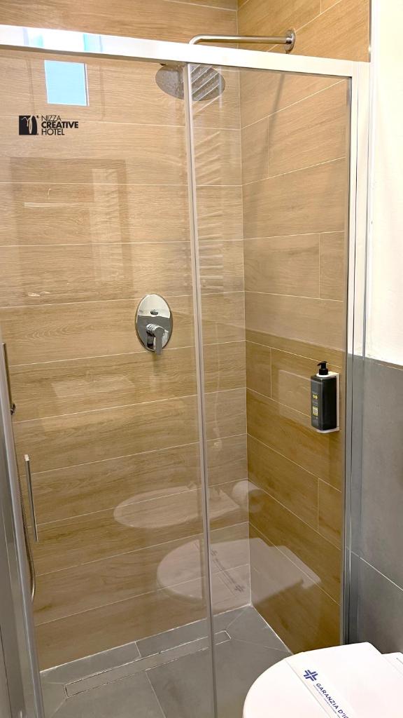 une douche avec une porte vitrée dans une salle de bain dans l'établissement Hotel Nizza Creative Hotel, à Rimini 109 autres photos