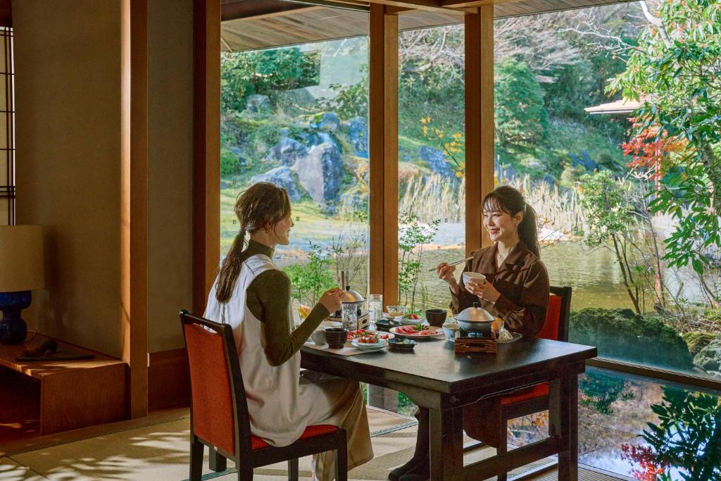 deux femmes assises à une table devant une fenêtre dans l'établissement Hakone Yunohana Prince Hotel, à Hakone