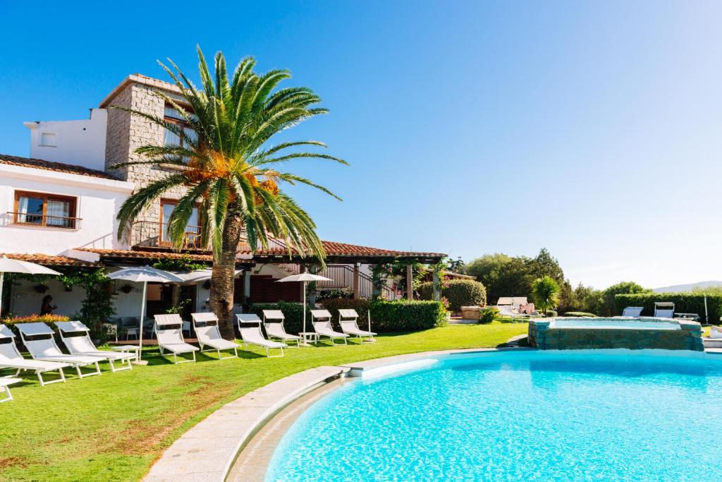 une piscine devant une maison avec des chaises et un palmier dans l'établissement Hotel Palumbalza Porto Rotondo, à Porto Rotondo