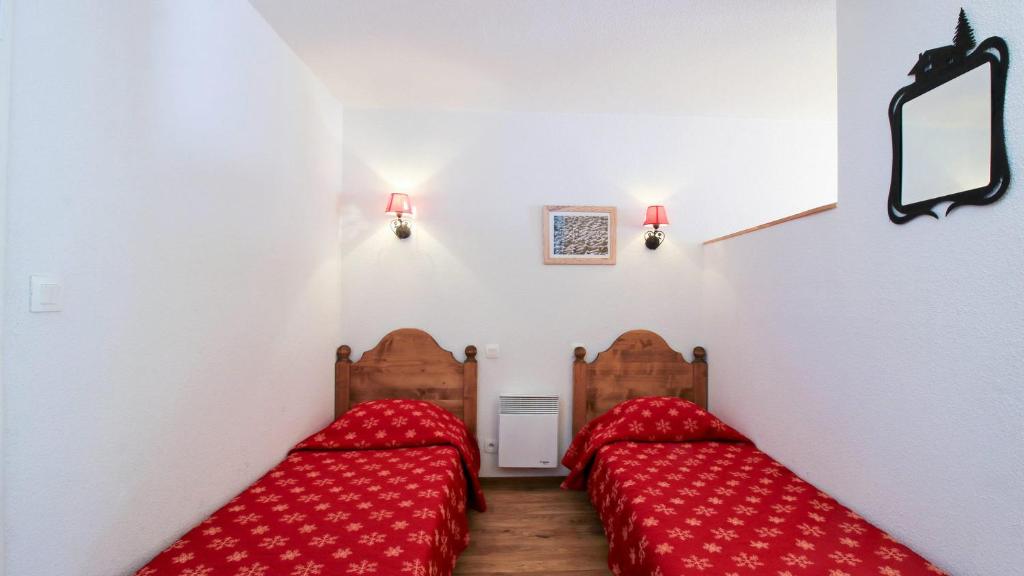 - 2 lits dans une chambre avec des draps rouges dans l'établissement Vacancéole - Résidence Central Park, à La Foux