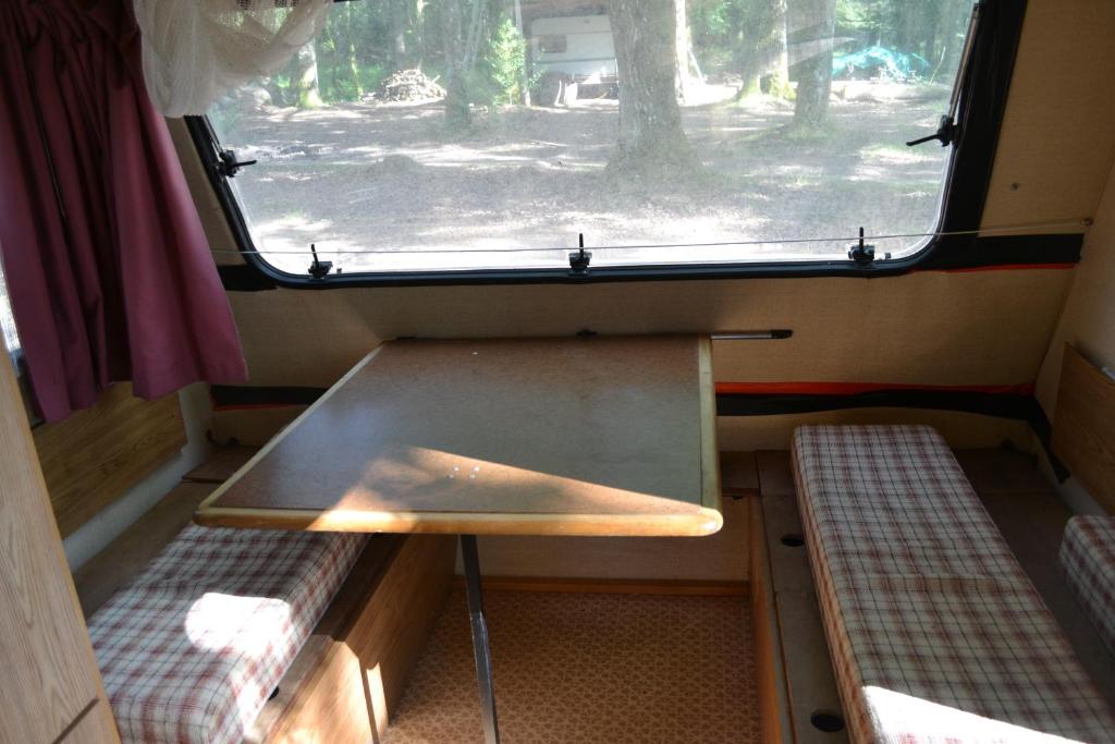 Cette petite chambre dispose d'une table et d'une fenêtre. dans l'établissement air naturel de camping moulin de malesse caravane, à Saint-Privat