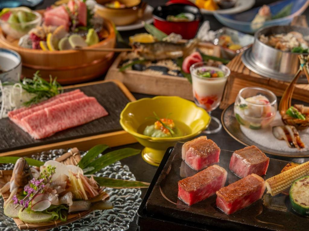 une table avec de nombreux types de denrées alimentaires sur les assiettes dans l'établissement KAMENOI HOTEL Kitsuregawa, à Sakura