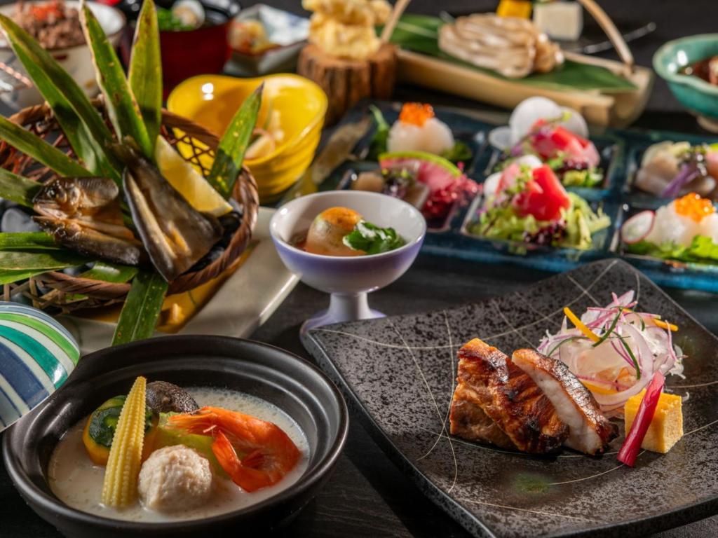 une table recouverte de assiettes et de bols de nourriture dans l'établissement KAMENOI HOTEL Kitsuregawa, à Sakura