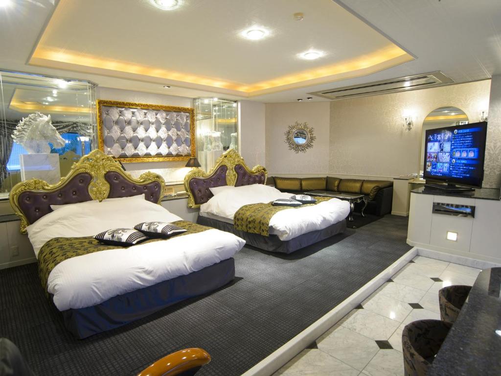 une chambre d'hôtel avec deux lits et une télévision à écran plat dans l'établissement Hotel Le Club PLUS 1 福岡新宮 -Adult Only-, à Shingū