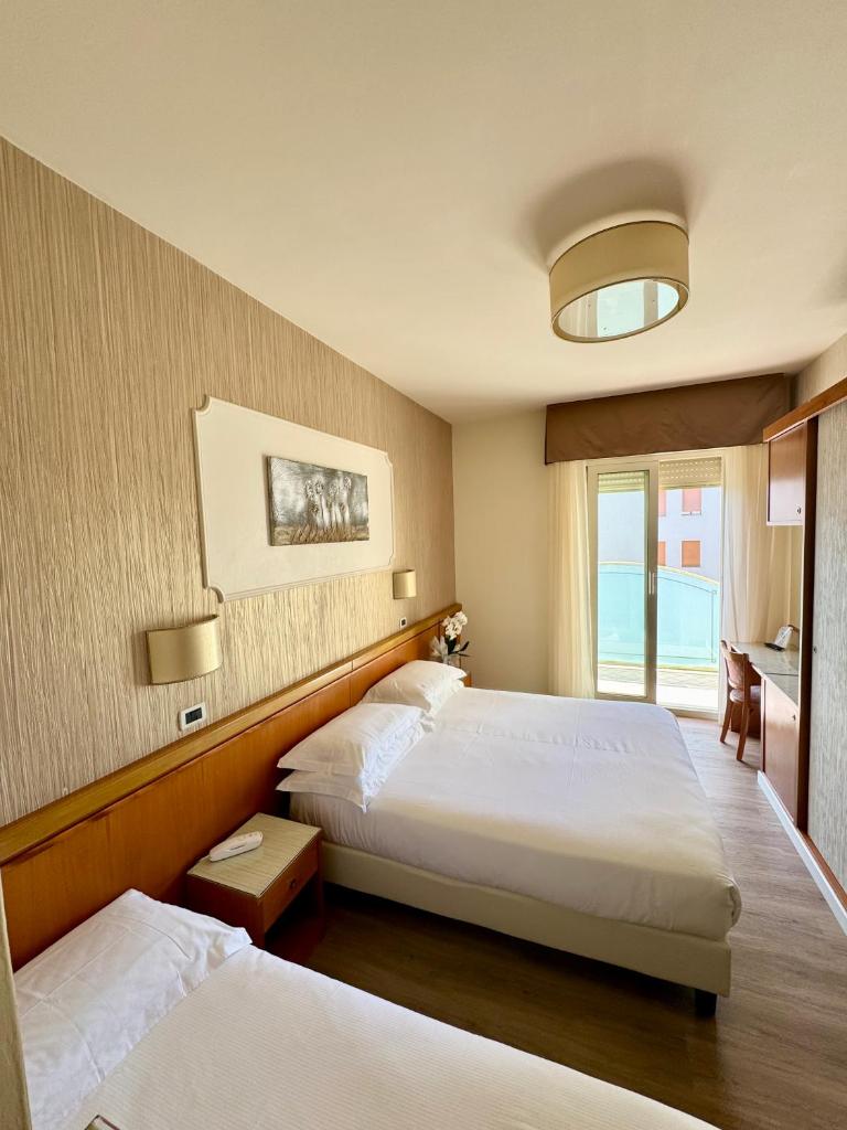 une chambre d'hôtel avec deux lits et une fenêtre dans l'établissement Hotel Alexander, à Milano Marittima 94 autres photos