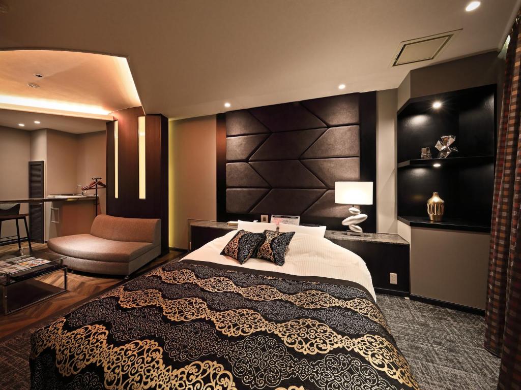 une chambre avec un grand lit et une chaise dans l'établissement Hotel Le Club PLUS 1 福岡新宮 -Adult Only-, à Shingū