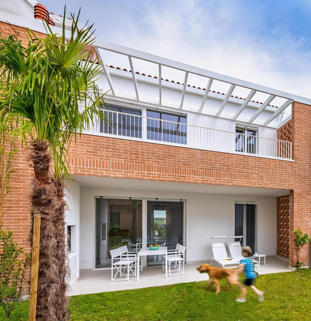 un enfant marchant un chien devant une maison dans l'établissement Pareus Beach Resort, à Caorle