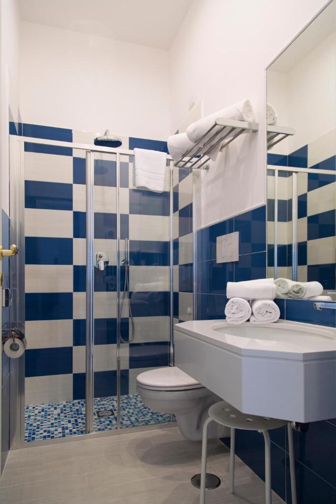 La salle de bains bleue et blanche est pourvue de toilettes et d'une douche. dans l'établissement Hotel Crawford, à Sant'Agnello