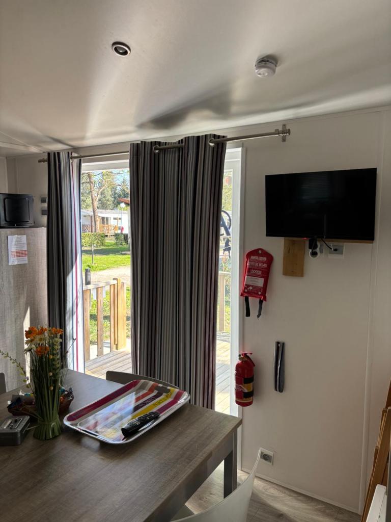 Cette chambre dispose d'une table, d'une télévision et d'une fenêtre. dans l'établissement Mobilhome Avengers Camping du Ried, à Boofzheim