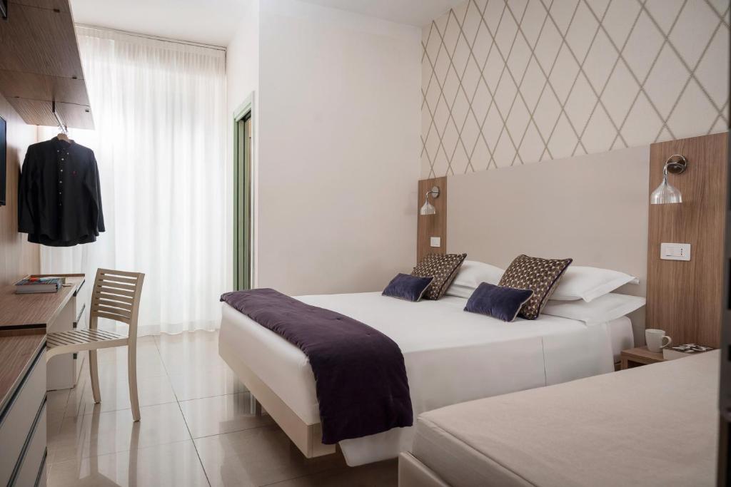une chambre d'hôtel avec deux lits et une fenêtre dans l'établissement Hotel Calypso- Rimini Marina Centro, à Rimini