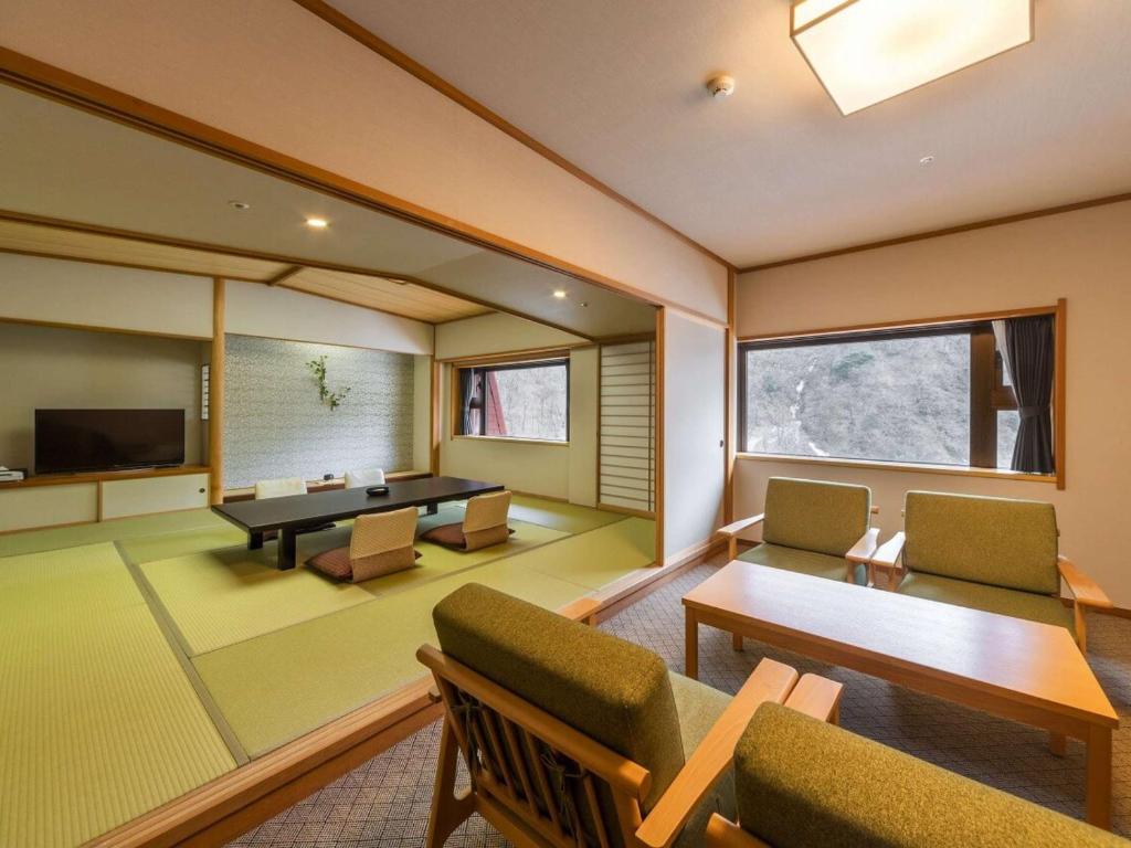 une pièce avec une table, des chaises et une télévision dans l'établissement Kurobe Unazukionsen Yamanoha, à Kurobe