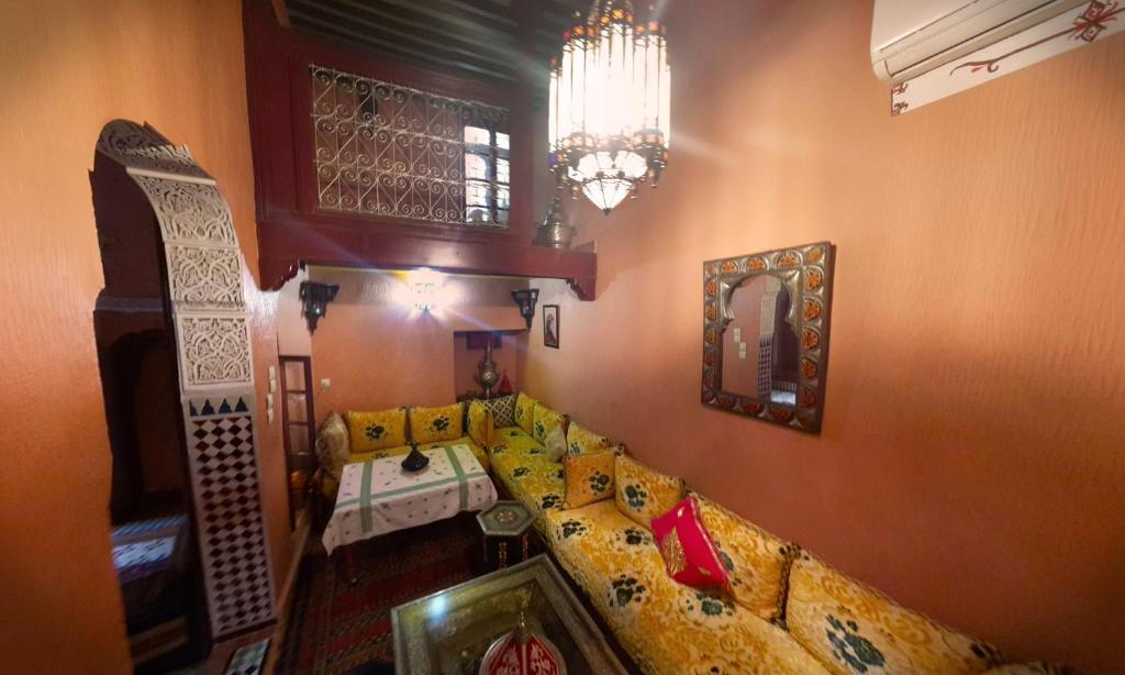 un salon avec un canapé jaune et un lustre dans l'établissement Riad Atika Mek, à Meknès