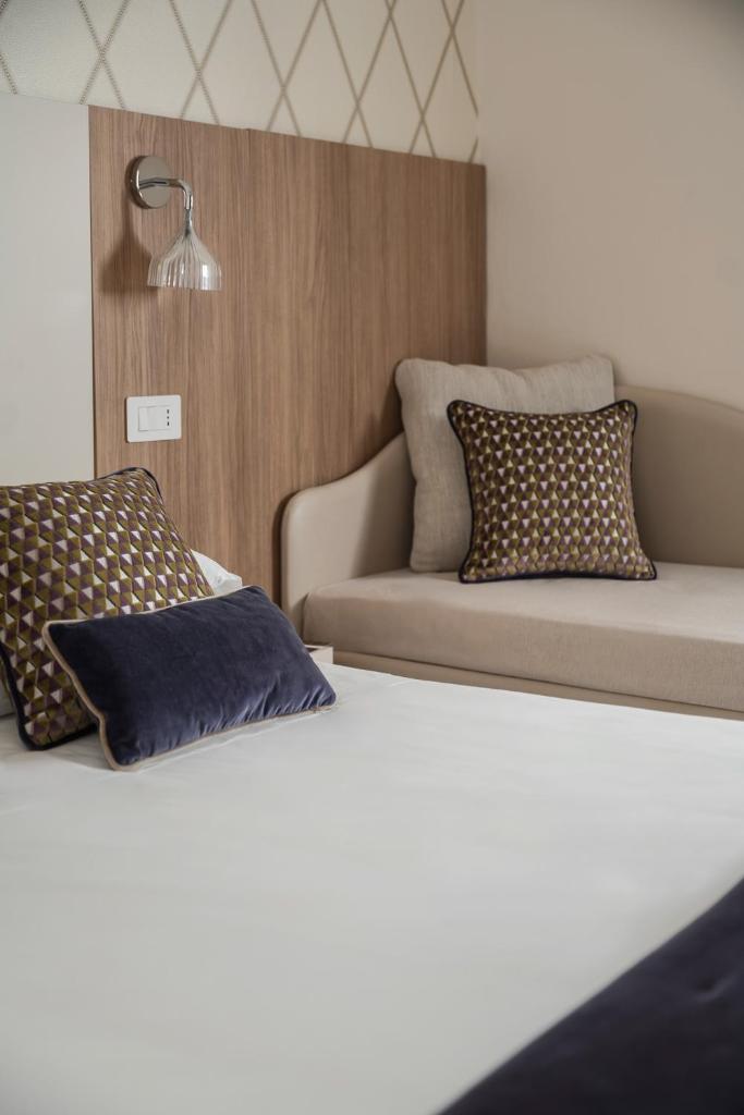 une chambre d'hôtel avec deux lits et un canapé dans l'établissement Hotel Calypso- Rimini Marina Centro, à Rimini