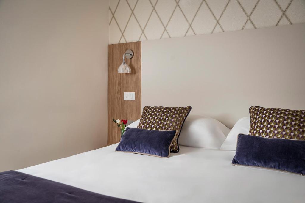 une chambre avec un lit blanc avec des oreillers bleus dans l'établissement Hotel Calypso- Rimini Marina Centro, à Rimini