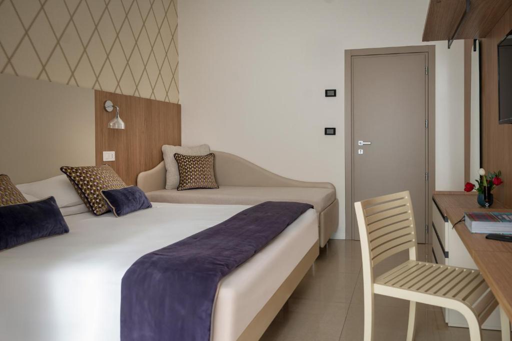 une chambre d'hôtel avec un lit et une chaise dans l'établissement Hotel Calypso- Rimini Marina Centro, à Rimini