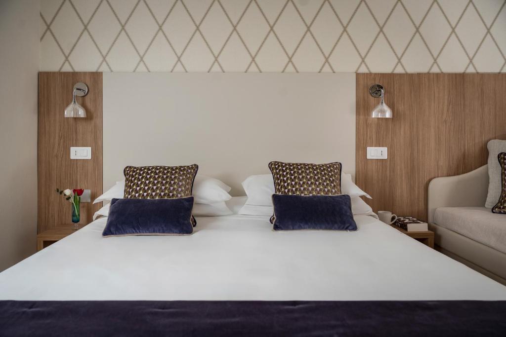une chambre avec un grand lit blanc avec des oreillers bleus dans l'établissement Hotel Calypso- Rimini Marina Centro, à Rimini 73 autres photos