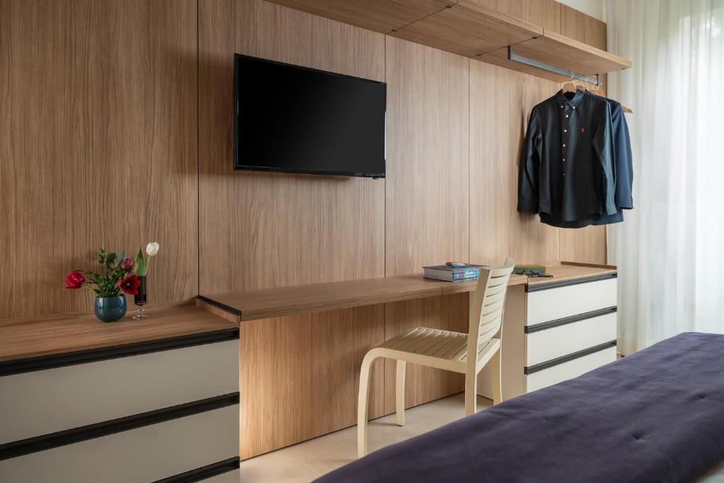 - une chambre avec un bureau et une télévision murale dans l'établissement Hotel Calypso- Rimini Marina Centro, à Rimini
