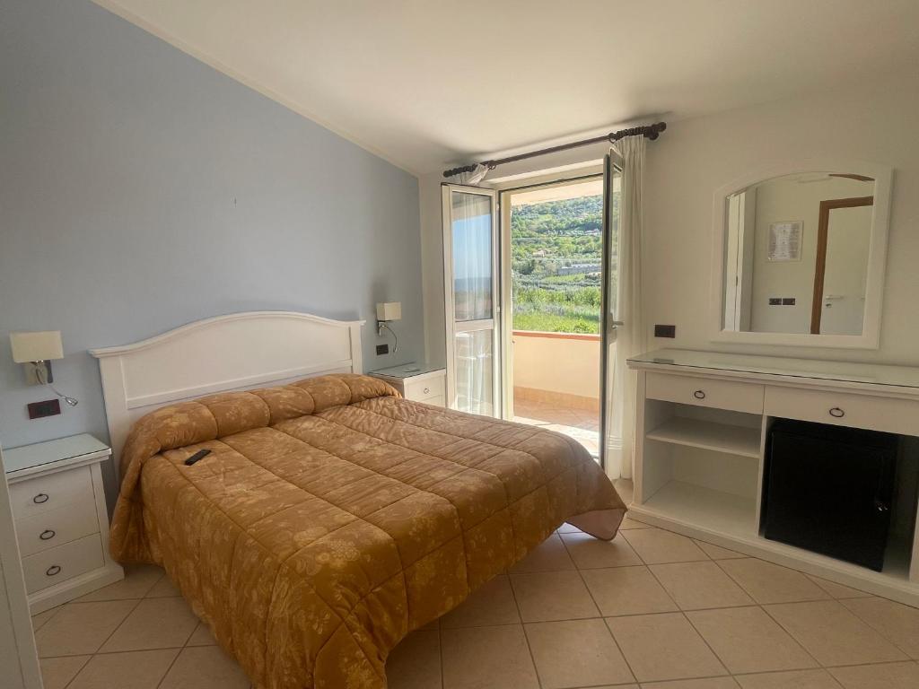 une chambre avec un lit, un miroir et une fenêtre dans l'établissement Hotel Ristorante Colleverde, à Santa Maria di Castellabate