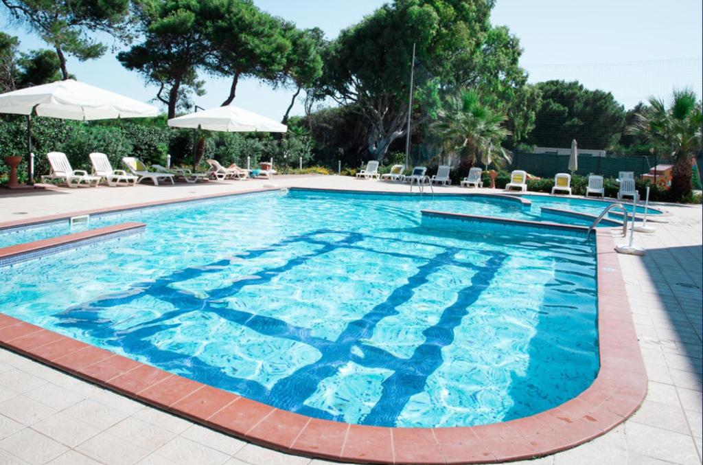 une grande piscine avec chaises et parasols dans l'établissement Stella Maris Hotel, à Marina di Ginosa