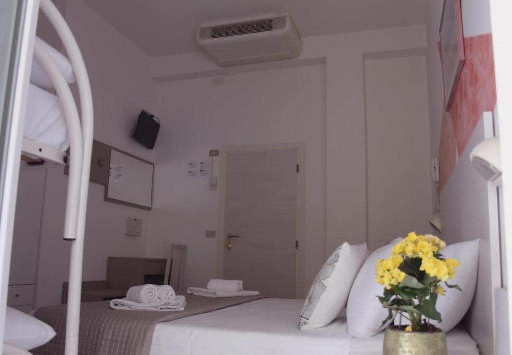 Cette chambre dispose d'un lit avec un vase de fleurs jaunes. dans l'établissement Alevon Hotel, à Rimini