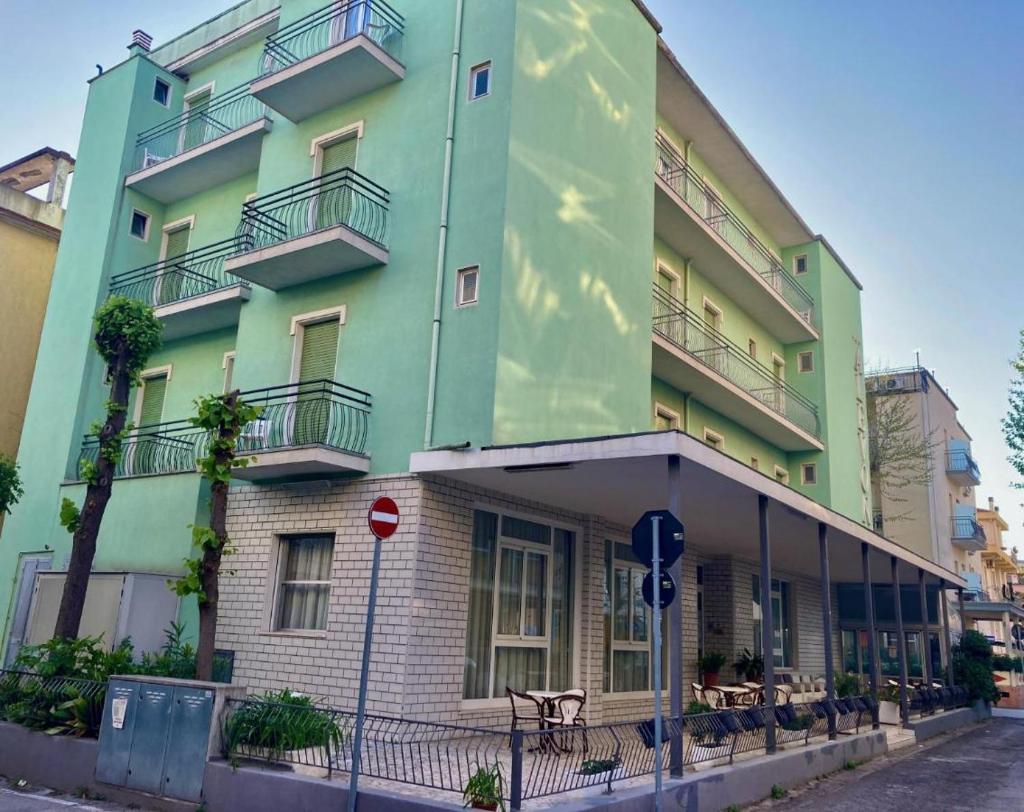 un bâtiment vert avec un banc devant dans l'établissement Alevon Hotel, à Rimini