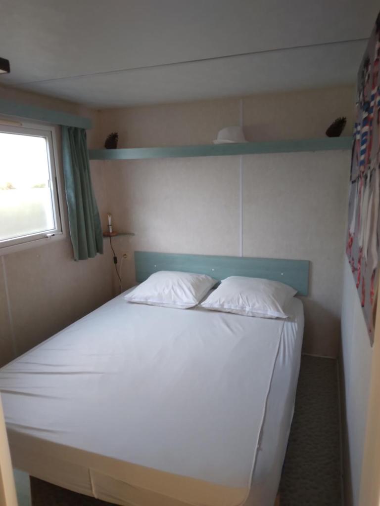 une chambre avec un lit avec des draps blancs et une fenêtre dans l'établissement les marguerites, à Mimizan