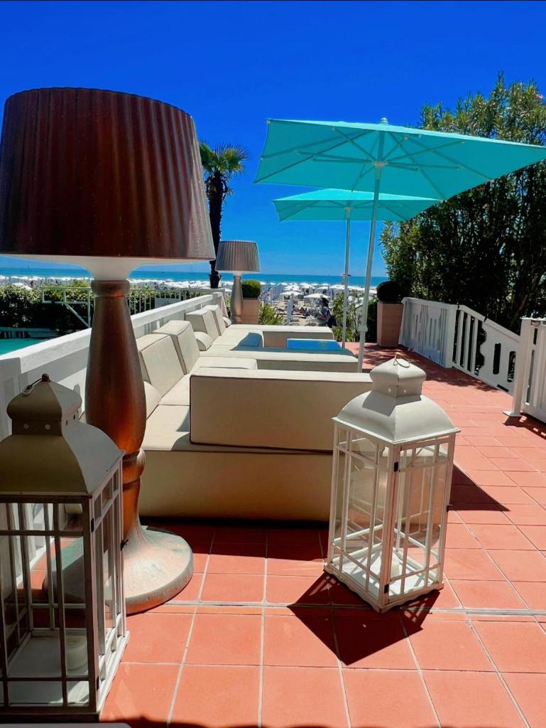 d'une terrasse avec un canapé, un parasol bleu et des lumières. dans l'établissement Hotel Savoy, à Caorle