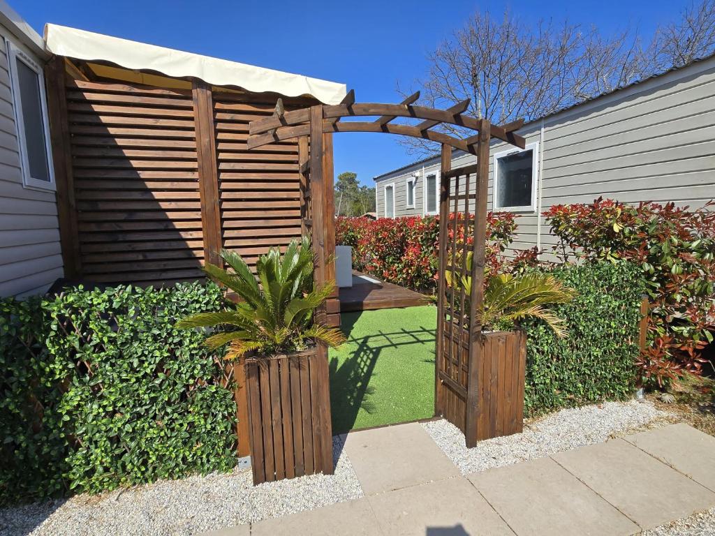 une pergola en bois avec deux plantes dans une cour dans l'établissement Mobil home tout confort au Camping Les Viviers, Cap Ferret, à Claouey