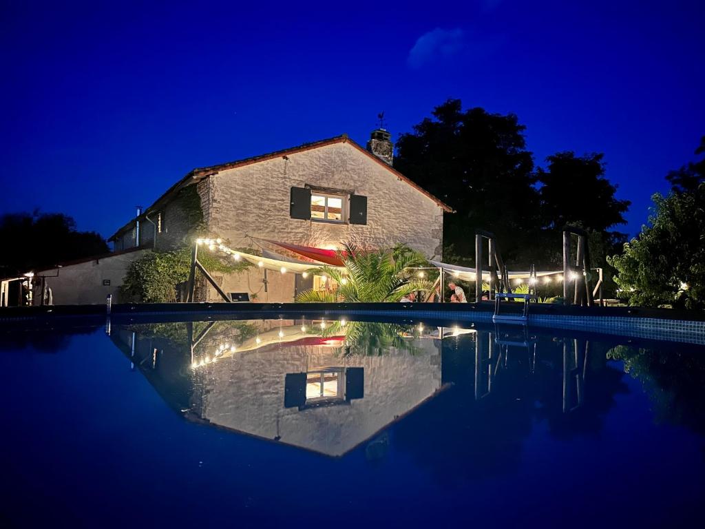 une maison avec réflexion dans une piscine la nuit dans l'établissement Pays de Joie - Caravan La Bohème, à Saint-Macoux