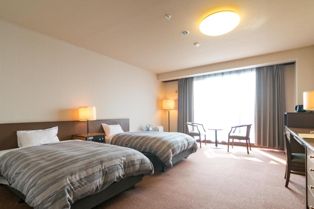 une chambre d'hôtel avec deux lits, une table et des chaises dans l'établissement Tokachi Makubetsu Onsen Grandvrio Hotel, à Obihiro