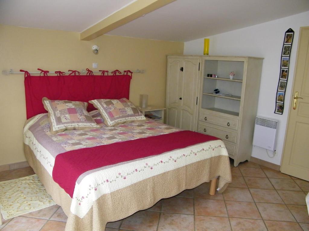 une chambre avec un grand lit avec une tête de lit rouge dans l'établissement Domaine du bois gîte Marion, à Galargues 20 autres photos