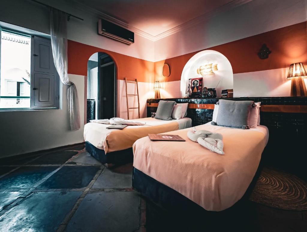 deux lits dans une chambre aux murs orange dans l'établissement Riad Lauriers Blancs, à Marrakech 37 autres photos