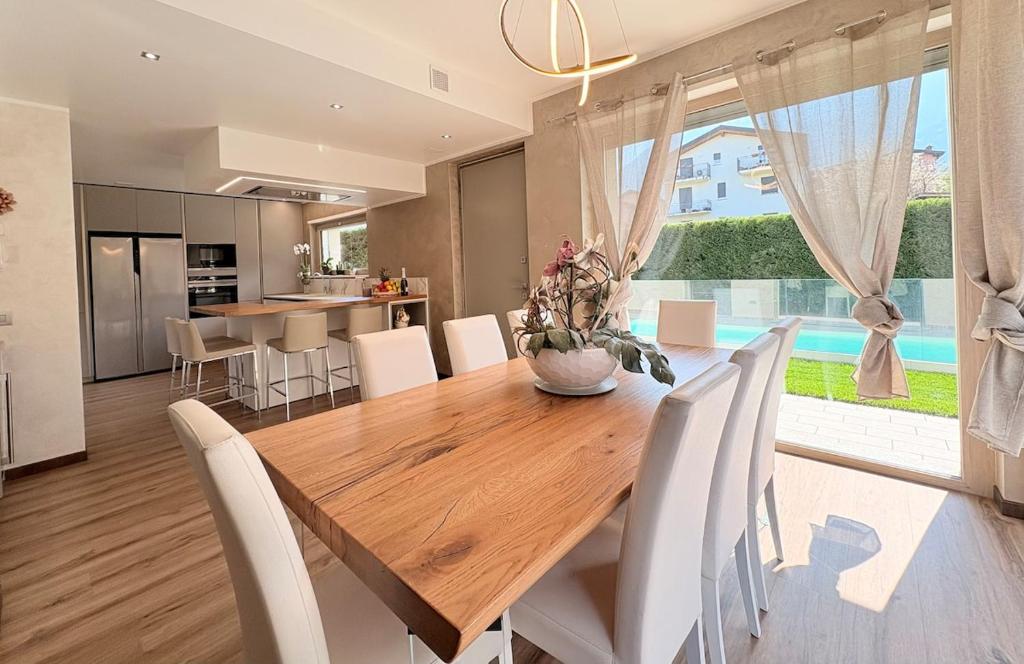une salle à manger avec une table en bois et des chaises blanches dans l'établissement Serenity villa - Lake Como, à Colico