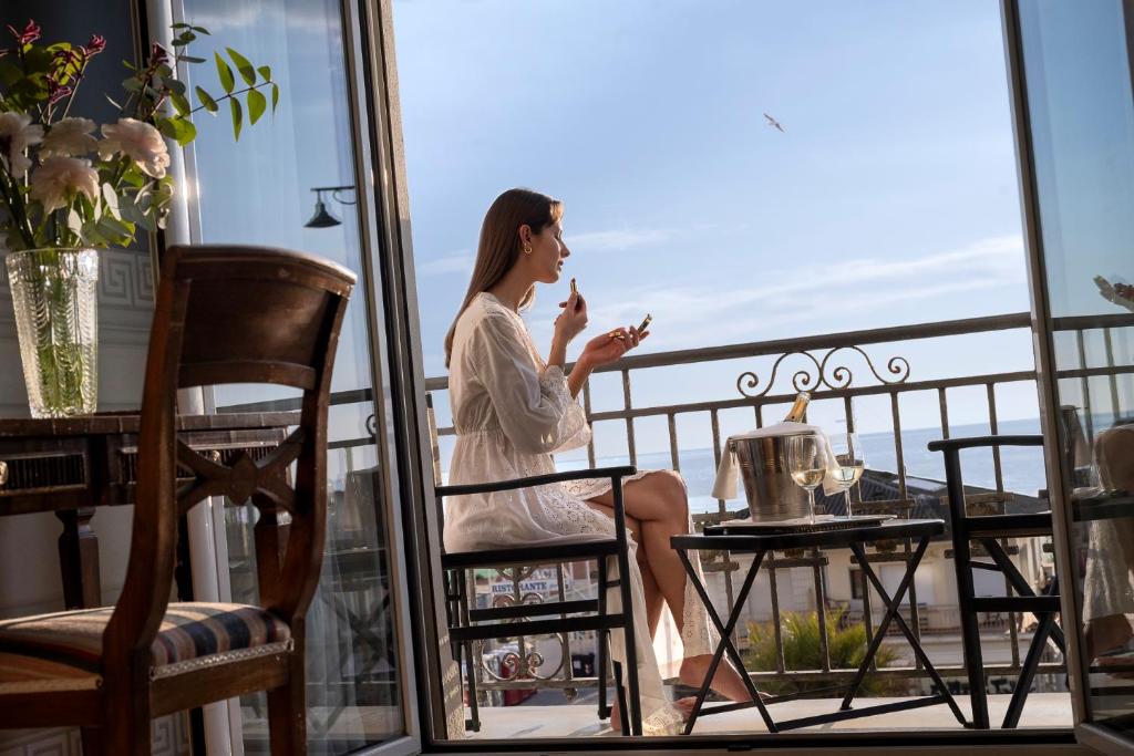 une femme assise sur un balcon donnant sur la fenêtre dans l'établissement Palace Hotel, à Viareggio