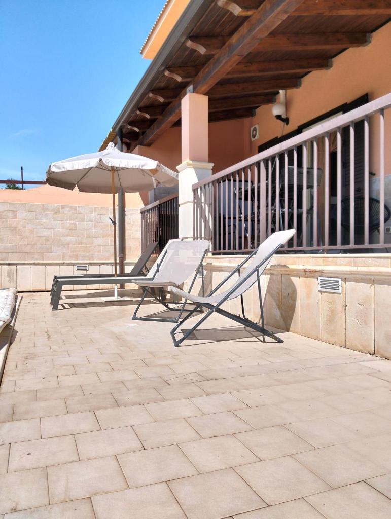 - 2 chaises longues et un parasol sur la terrasse dans l'établissement HOME 65 Seafront With Private Pool, à Villaggio Azzurro