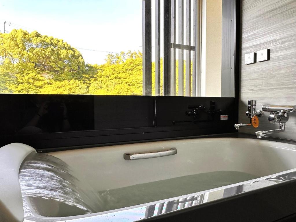 une baignoire dans une salle de bain avec une fenêtre dans l'établissement Arima Kirari, à Kobe